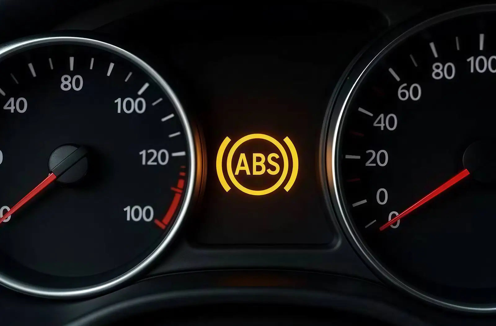 Shows a driver's view from behind the steering wheel at night on a wet highway, highlighting a yellow "ABS" warning icon illuminated on the center dashboard display.