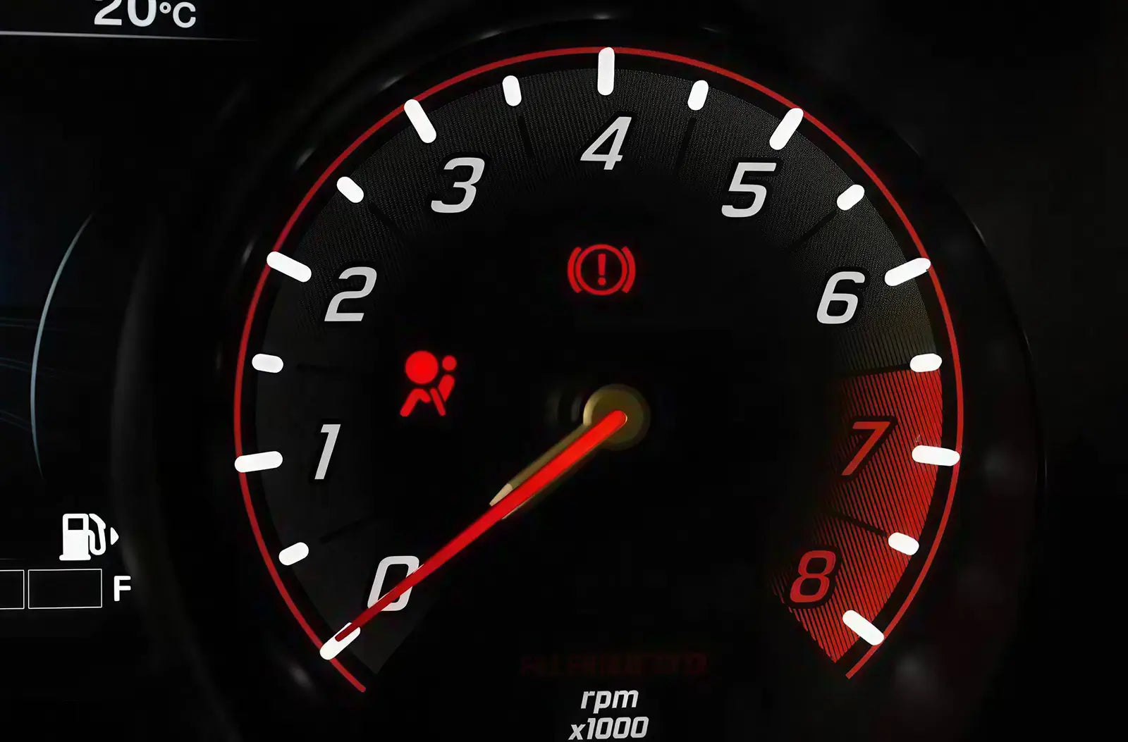 Close-up of an analog vehicle gauge cluster with a prominent red "Airbag / SRS" passenger safety warning symbol illuminated.