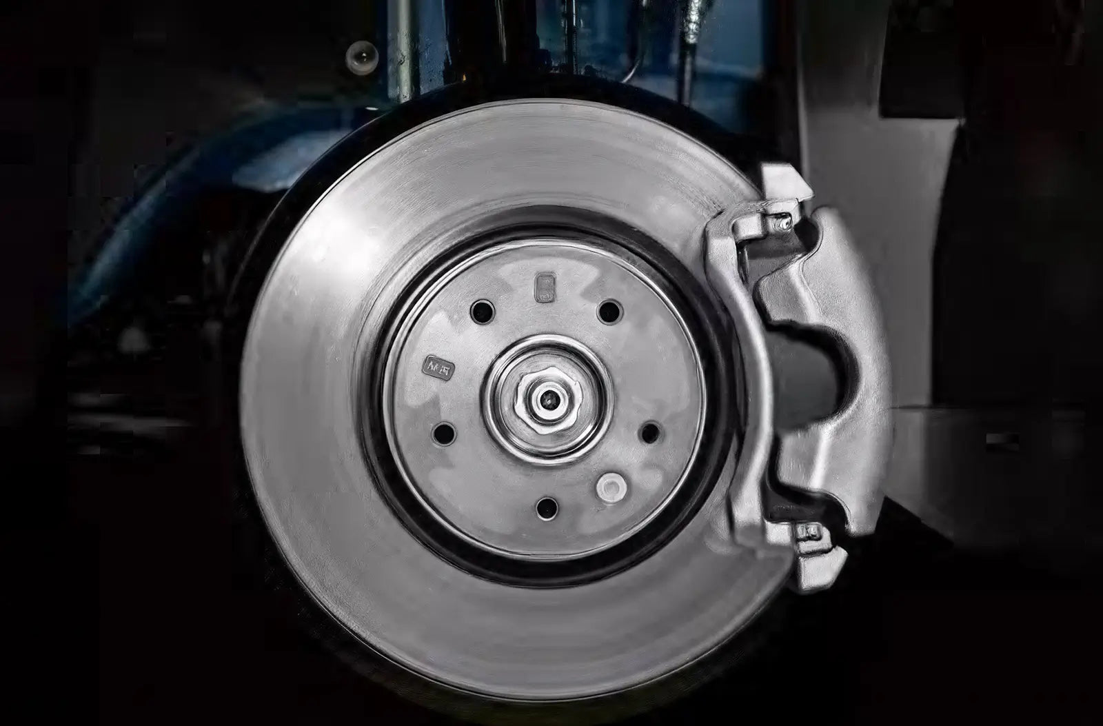 A close-up view from inside the footwell of a driver wearing a black leather boot pressing down hard on the vehicle's rubber brake pedal.