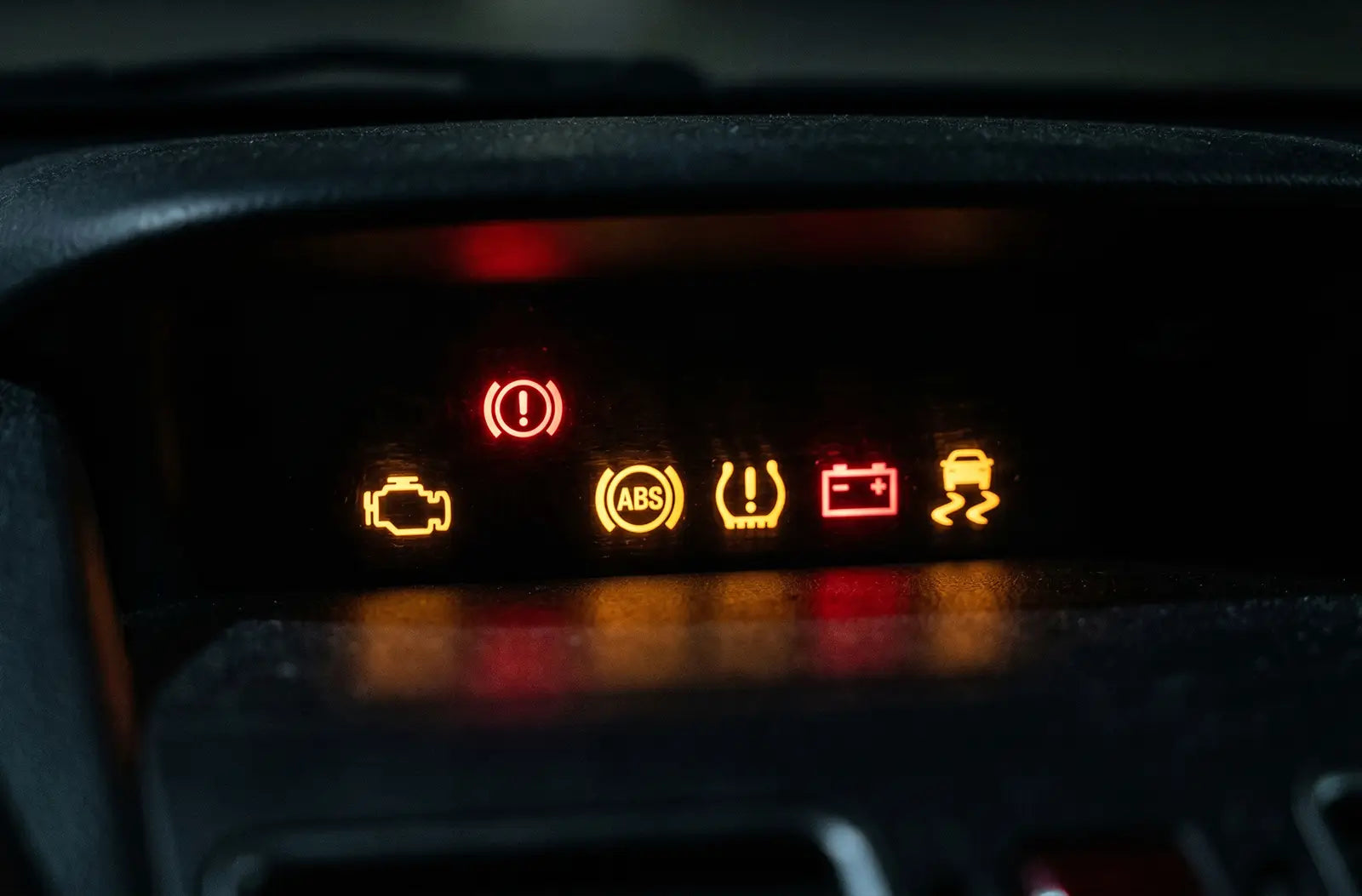 Shows a vehicle's digital dashboard cluster at night with multiple yellow and red warning icons lit up simultaneously, including the engine, ABS, and battery lights.