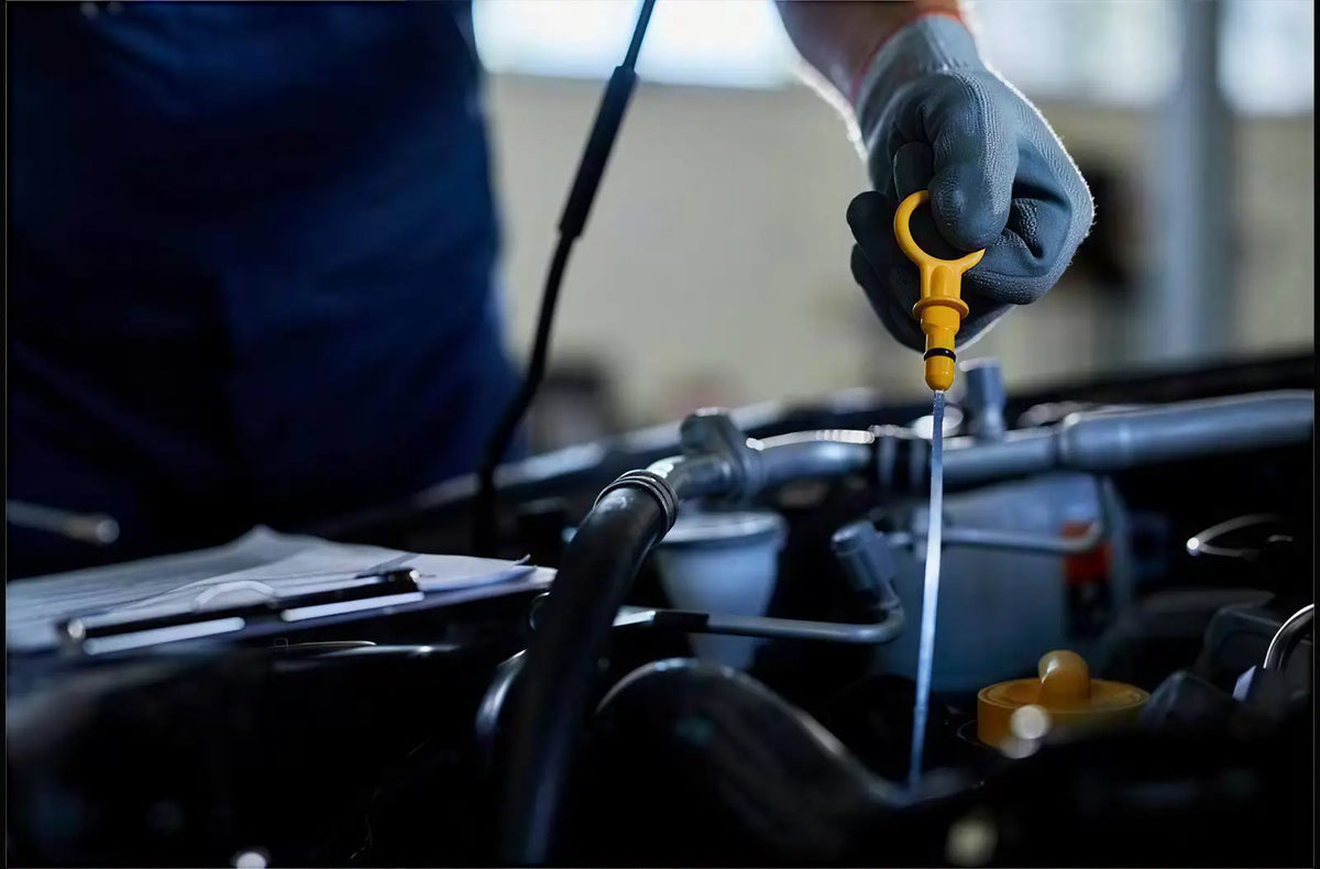 Shows a hand holding a handheld automotive diagnostic scan tool with a bright color interface screen in front of a car steering wheel.