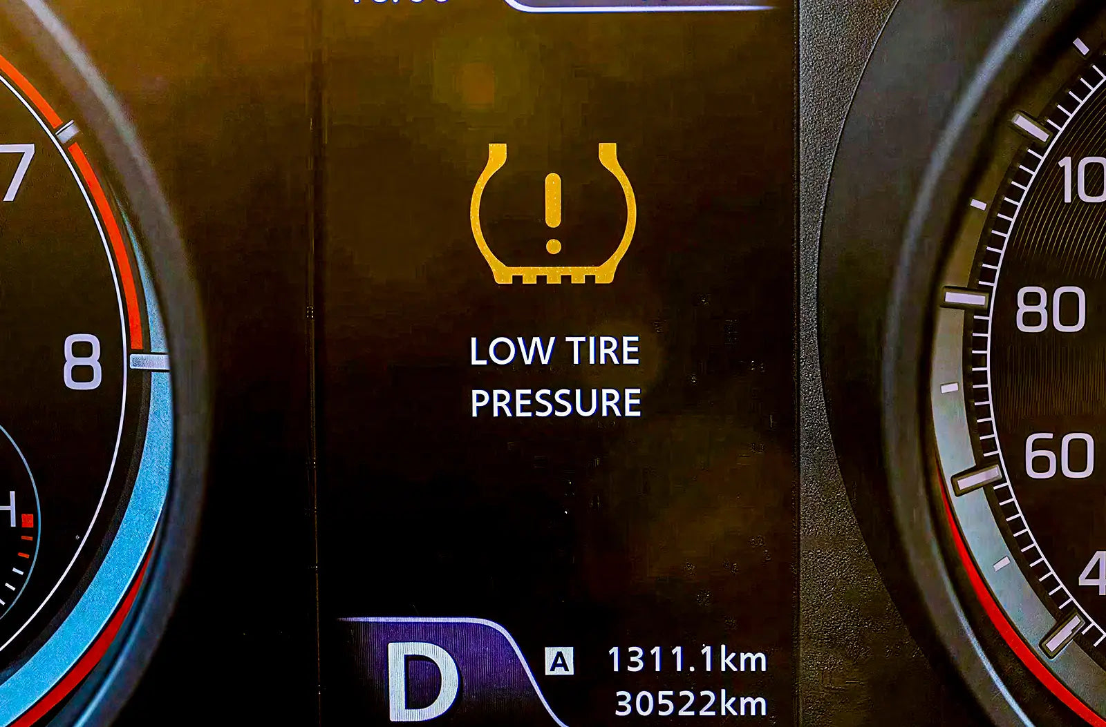 Shows a close-up profile of a car tire on a custom wheel rim, highlighting the metal valve stem where a tire pressure sensor is located.
